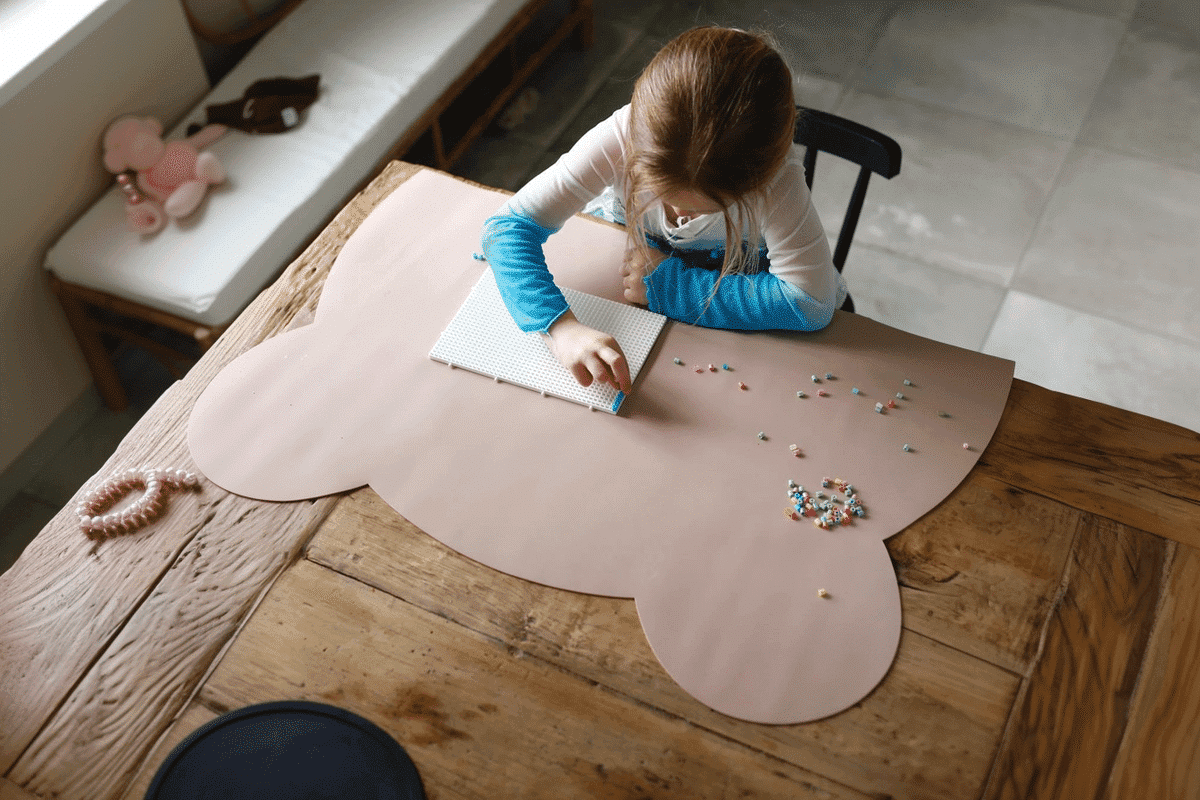 En pige sidder ved et bord og arbejder med strygeperler