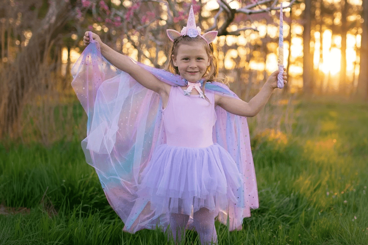 Enhjørning kostume. En pige iført et enhjørning kostume i en skov ved solnedgang