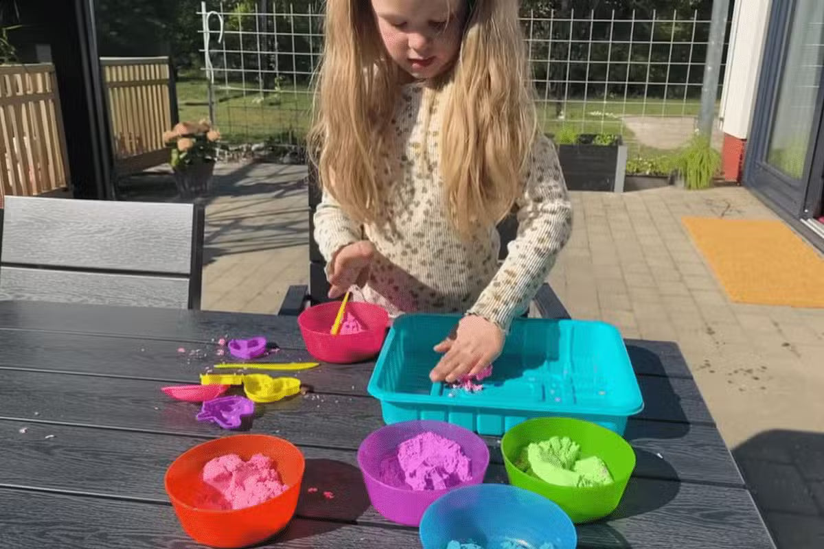 Kinetic Sand. En ung pige leger med kinetic sand i forskellige farver udenfor